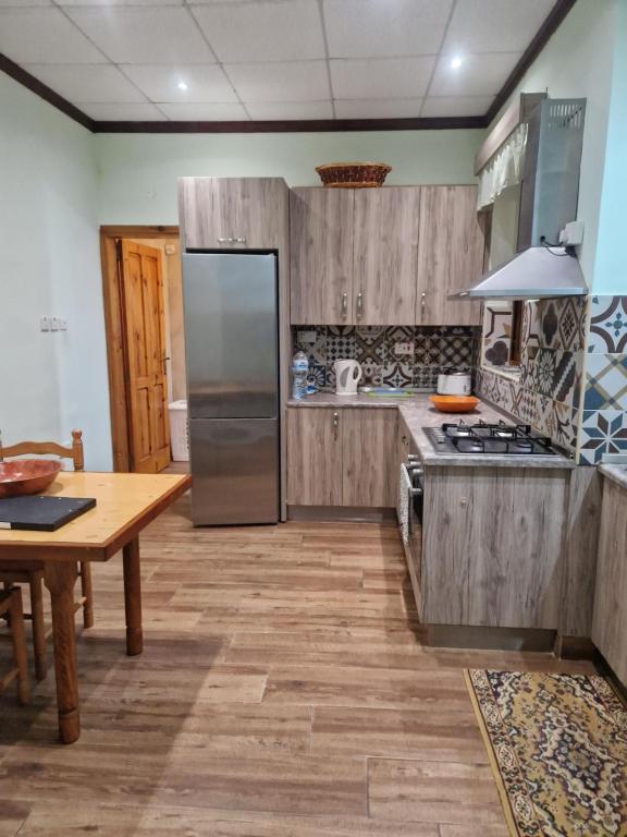 Għajn il-KbiraSir Patrick's rooms & hostel的厨房配有木制橱柜、桌子和冰箱。