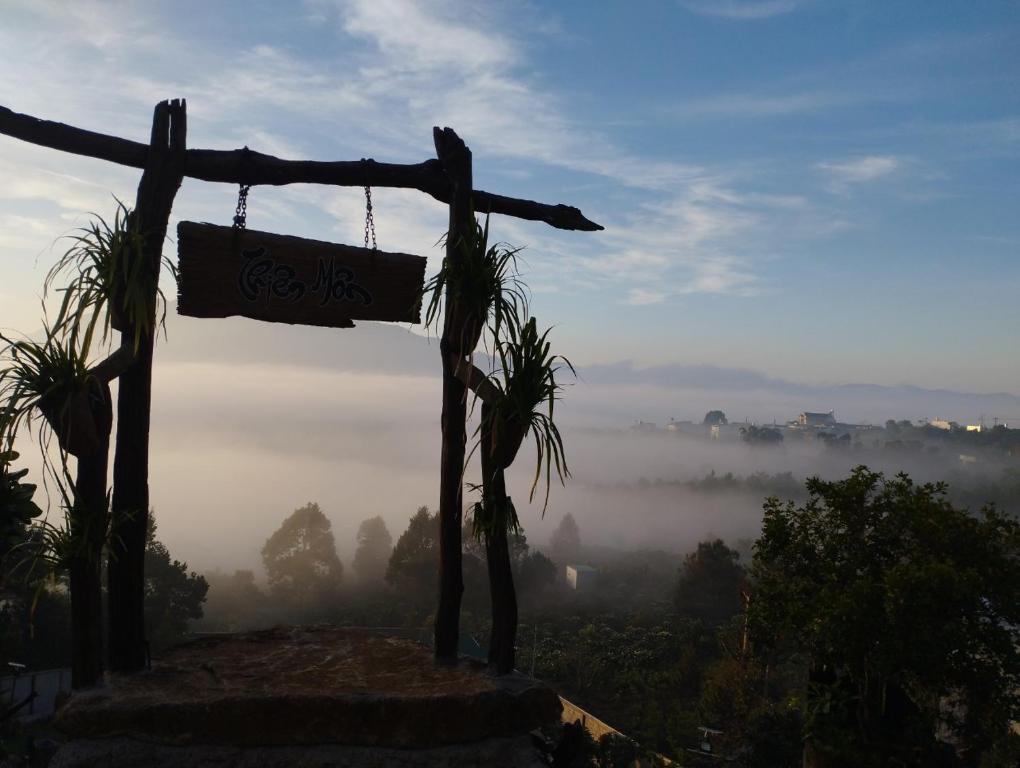 保禄Homestay Chân Quê的挂在有雾 ⁇ 的山谷的山坡上的柱子上的标志