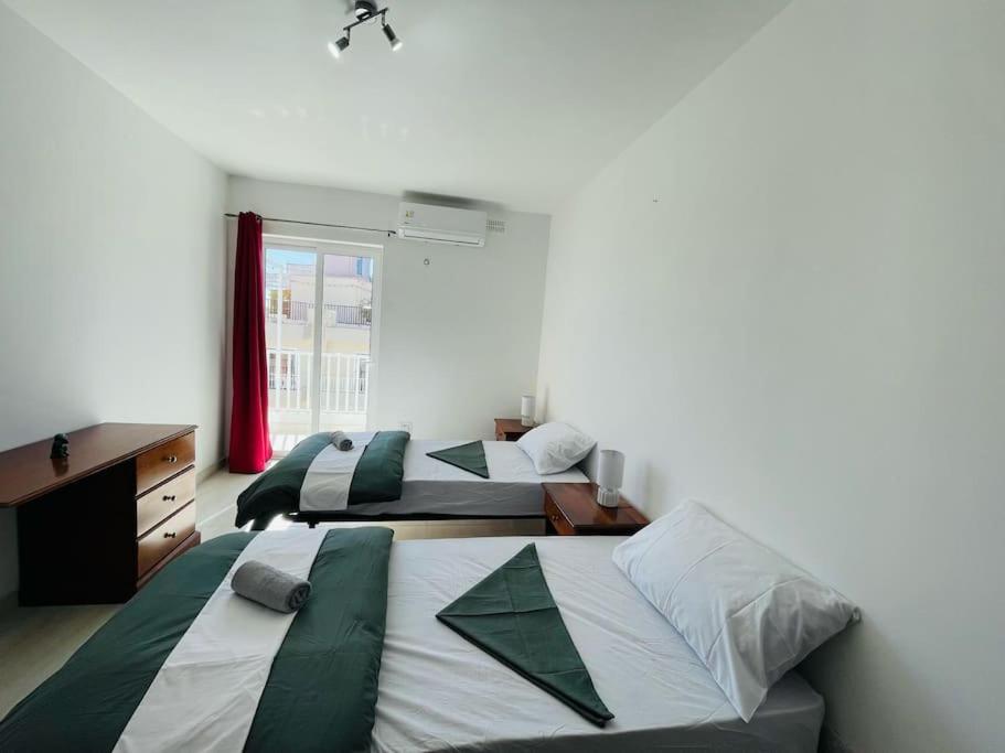 圣保罗湾城Coral Cove Comfort Apartment Room 3的一间卧室设有两张床、一张桌子和一个窗口。