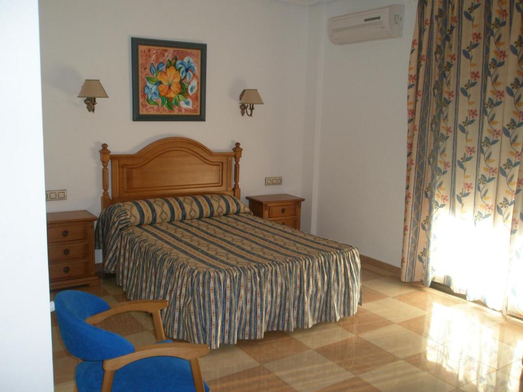 阿尔卡拉斯Hostal Los Rosales的一间卧室配有一张床和一张蓝色椅子