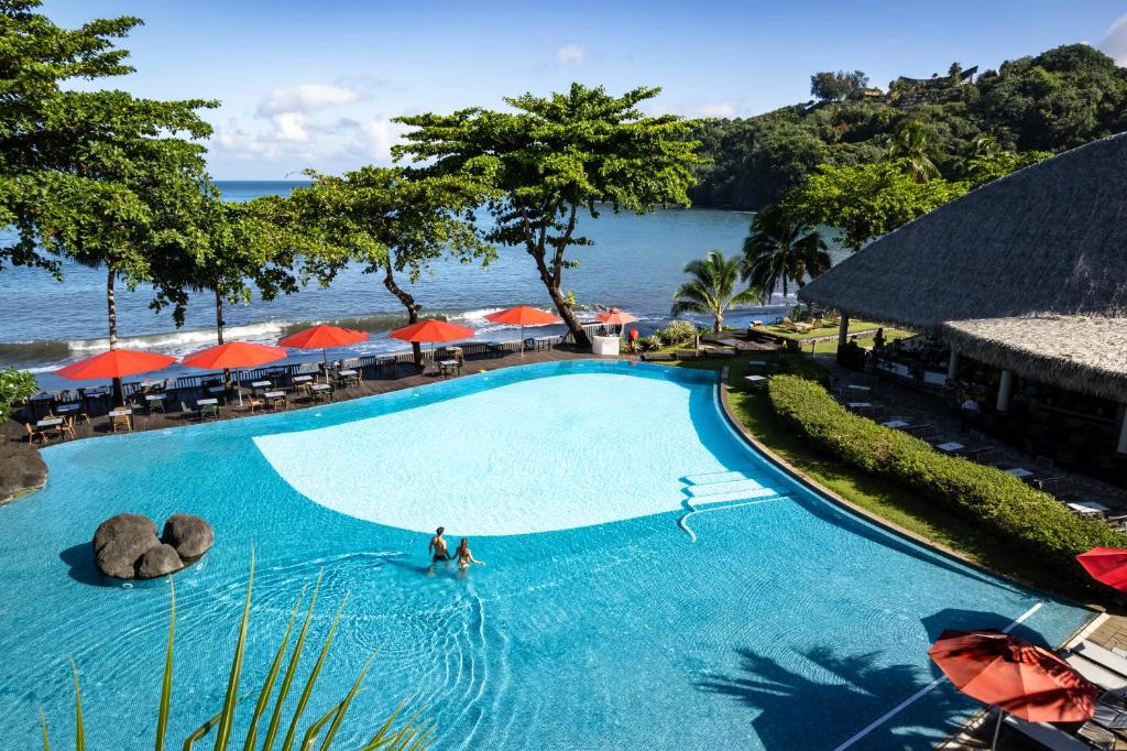 帕皮提Le Tahiti by Pearl Resorts的在海边游泳池游泳的人