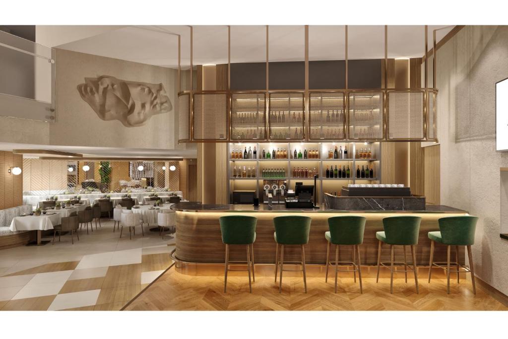 伊斯坦布尔Delta Hotels Istanbul West的餐厅设有1间带绿色椅子的酒吧
