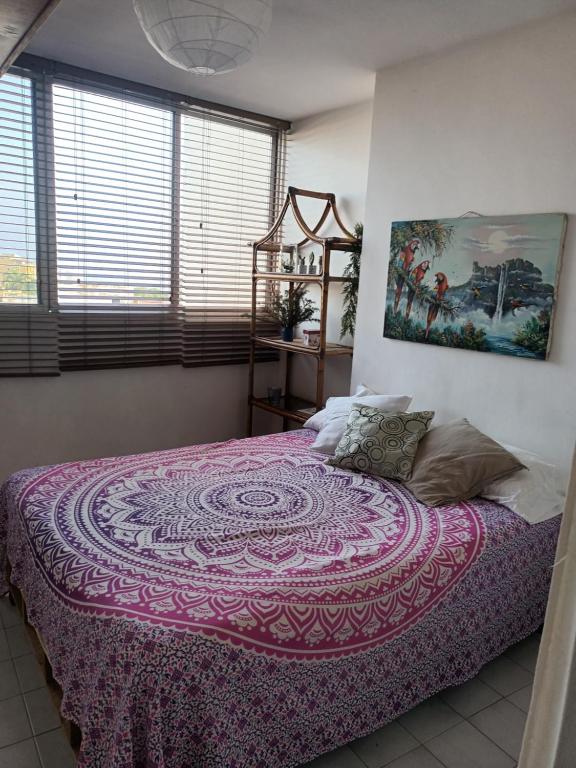 CaraballedaLas orquideas的一间卧室配有一张大床和紫色毯子