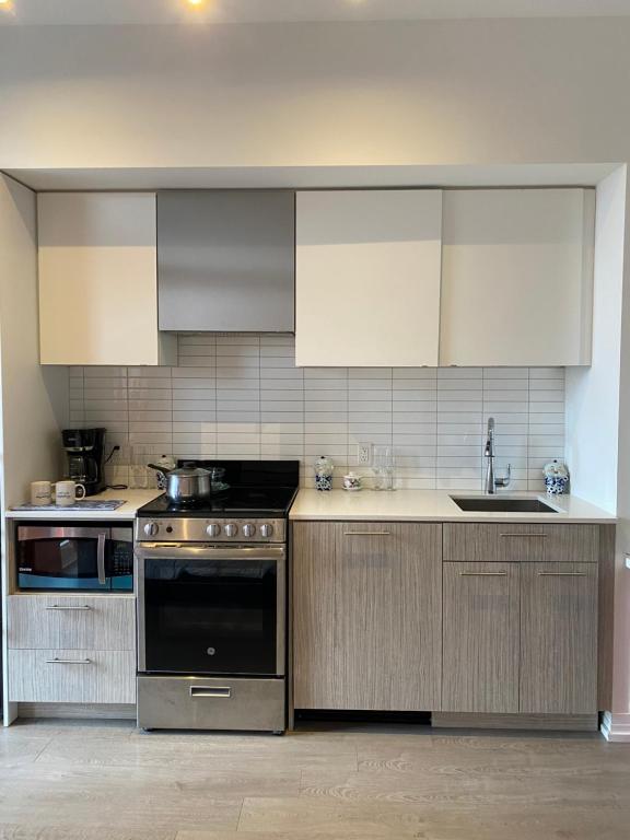 多伦多Cozy holiday home的厨房配有不锈钢用具和白色橱柜