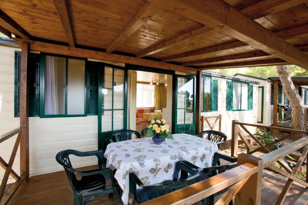 加利亚诺德尔卡波Camping Villaggio Santa Maria Di Leuca的一个带桌椅的屏蔽门廊