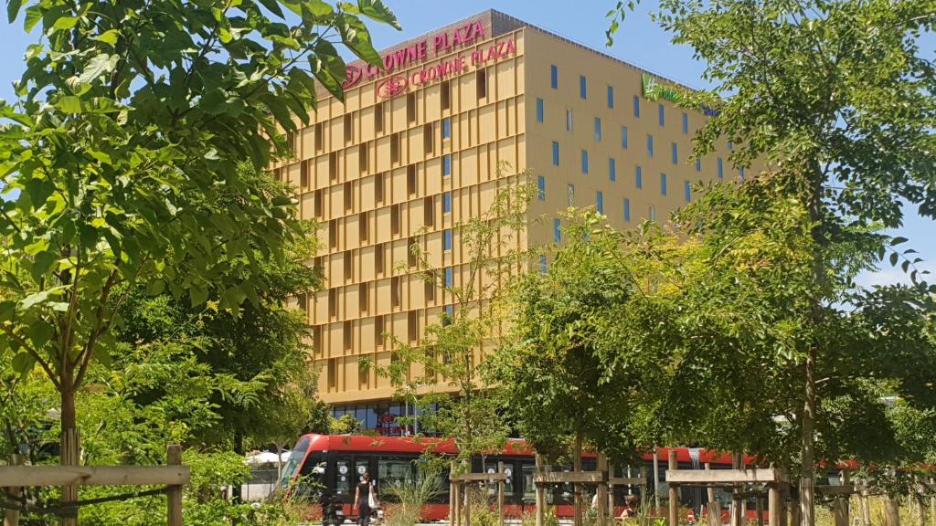 尼斯Crowne Plaza - Nice - Grand Arenas, an IHG Hotel的前面有一辆红色巴士的建筑