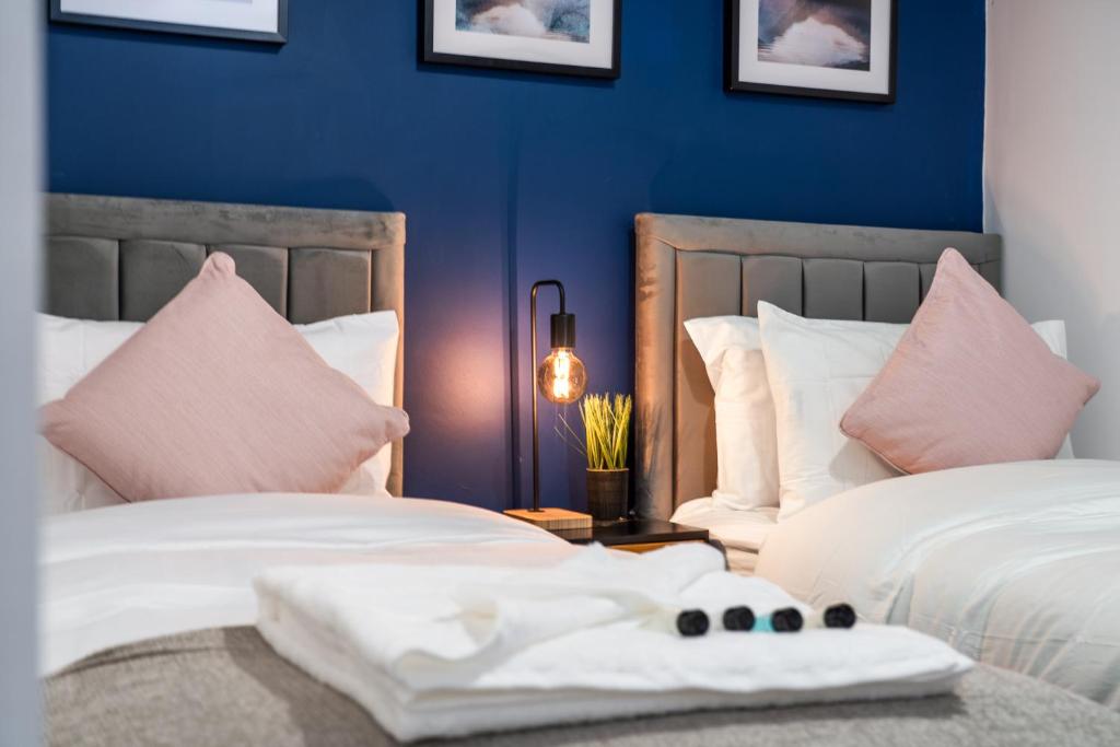 波特斯巴The Hertfordshire Hideaway的配有两张蓝色墙壁和粉红色枕头的客房内的床铺