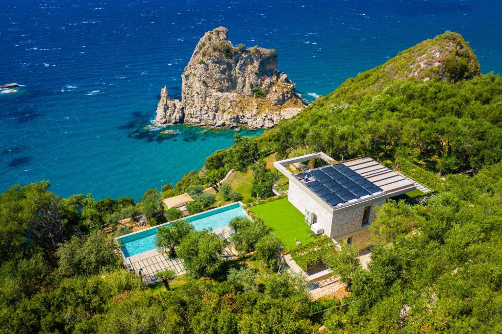 科孚镇Amberton Green Villas Corfu的海边小山上带太阳能电池板的房子