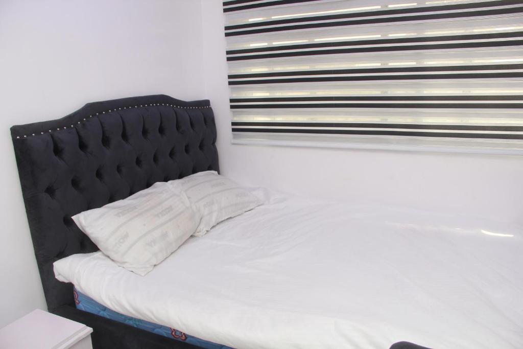 Festac Town3 bedroom apartment (fully furnished), Festac的一张白色的床,在房间里设有黑色床头板