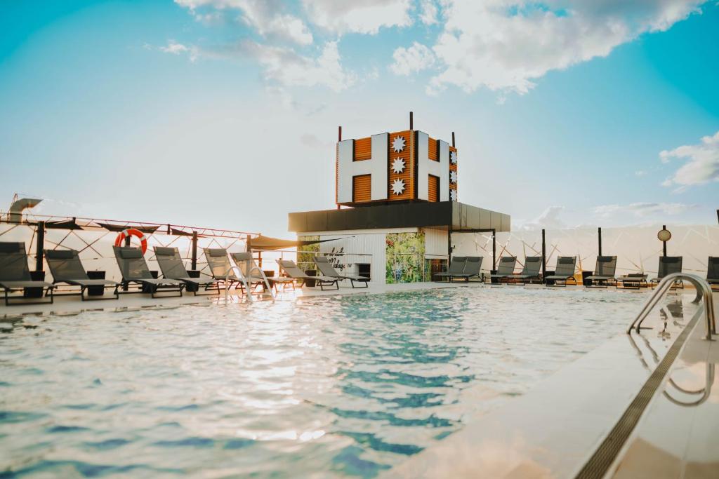 马拉加Hotel Málaga Nostrum Airport的一座带椅子的建筑屋顶上的游泳池