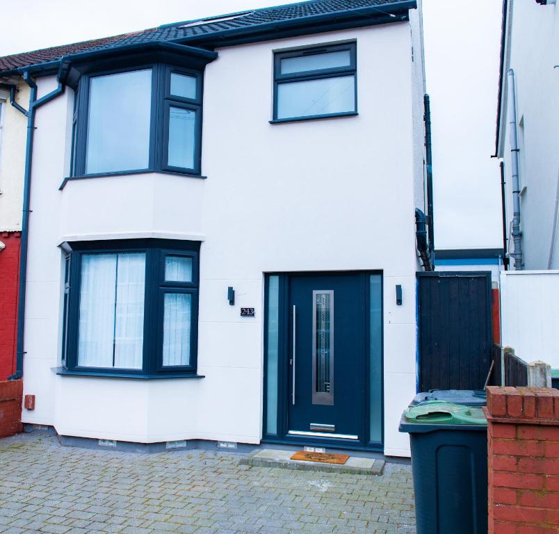 卢顿Newly Refurbished - Affordable Four Bedroom Semi-Detached House Near Luton Airport and Luton Hospital的一间白色的房子,有黑色的门,一个垃圾桶