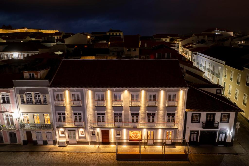 英雄港Açores Autêntico Boutique Hotel的一座白色的大建筑,晚上有灯