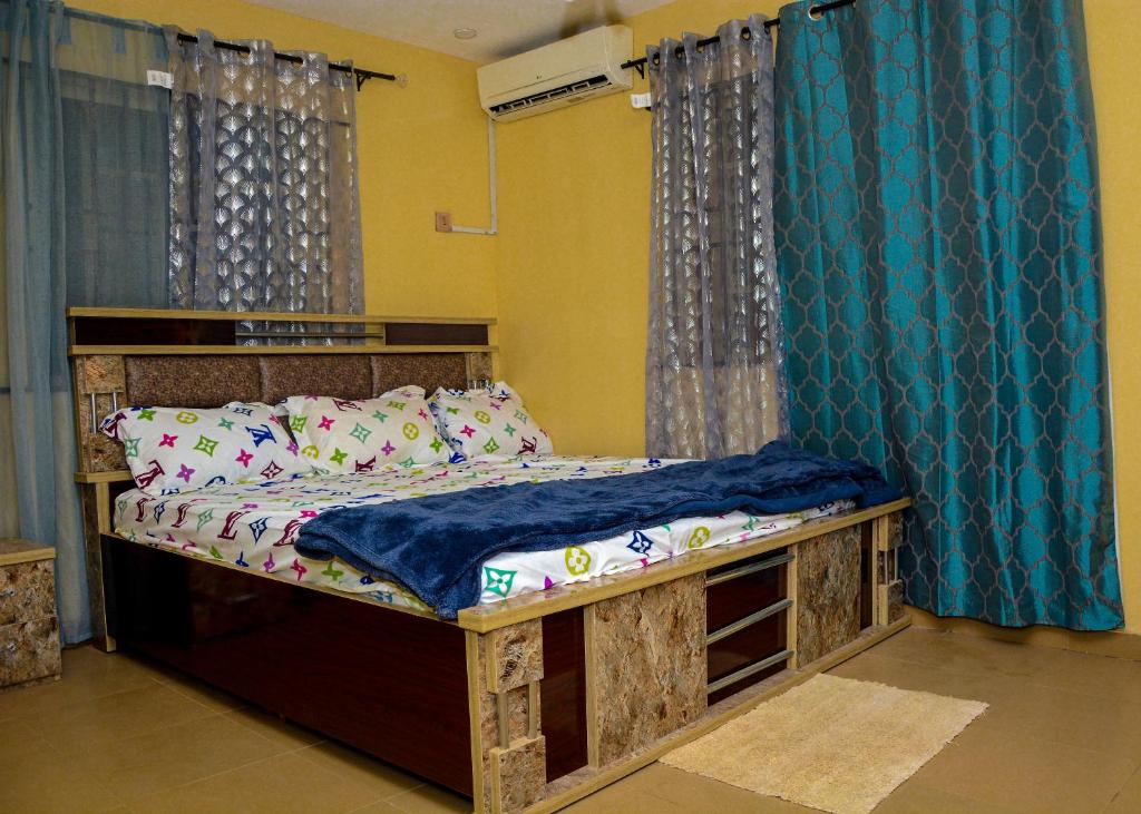 Suberu OjeRehoboth hotel, Apartment and Event services的一间卧室配有一张带蓝色窗帘的木床
