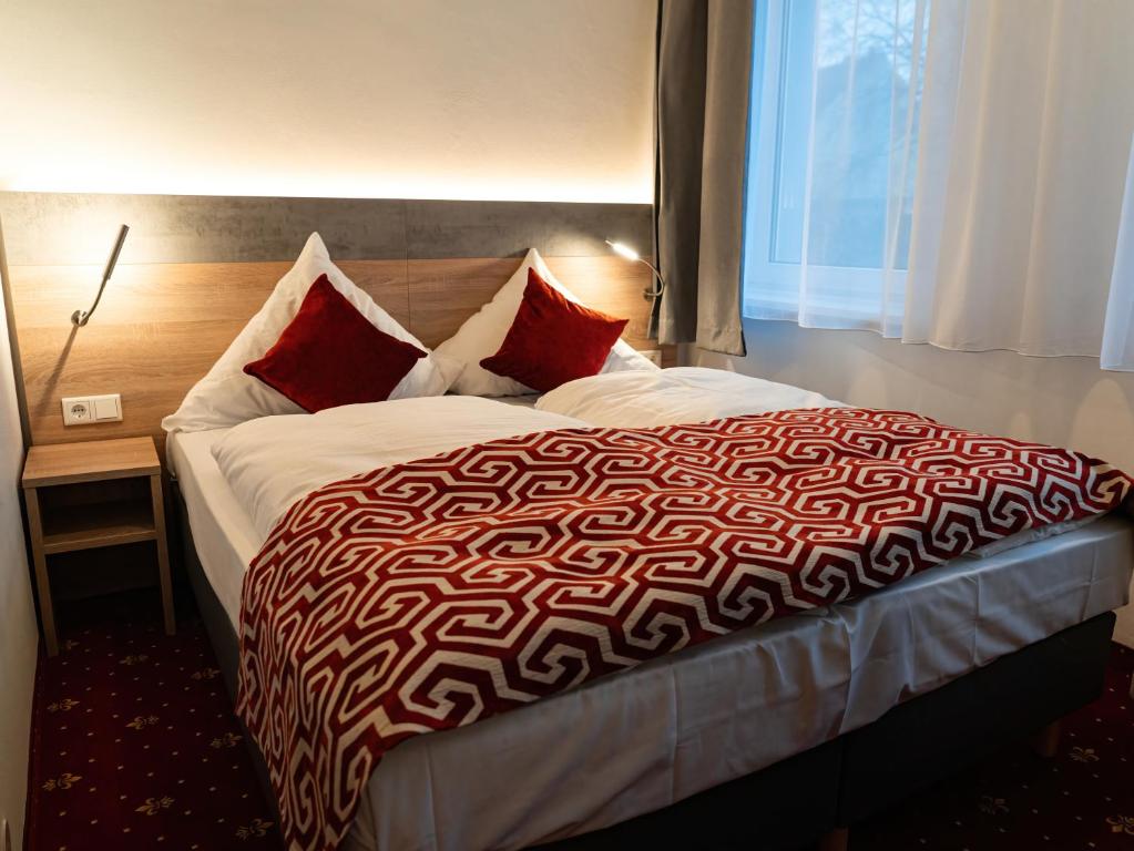 汉堡Hotel Stadion Stadt的一间卧室配有一张带红色枕头的大床
