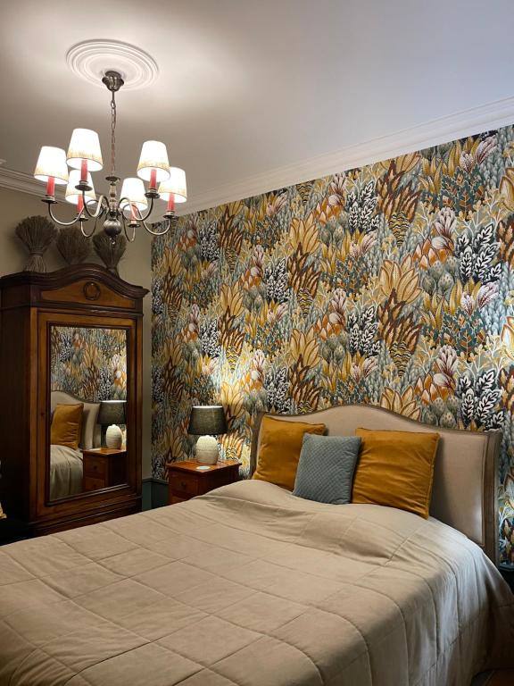Belleville-en-Beaujolais花园旅馆的一间卧室配有一张带花卉壁纸的大床