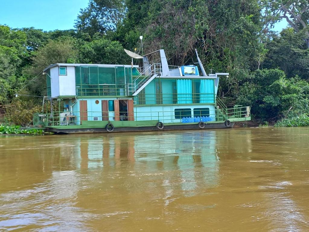 波科内Barco Casa Pantanal Toca da Onça的船屋坐在河上