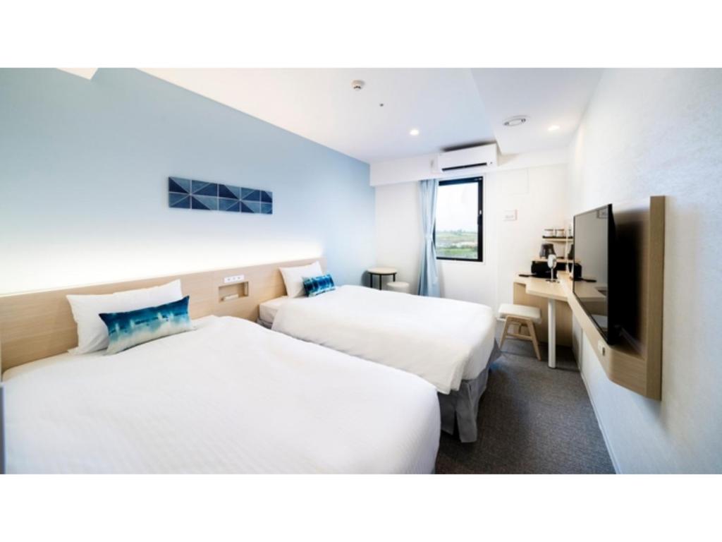 宫古岛Hotel Torifito Miyakojima Resort - Vacation STAY 79479v的一间酒店客房,设有两张床和电视