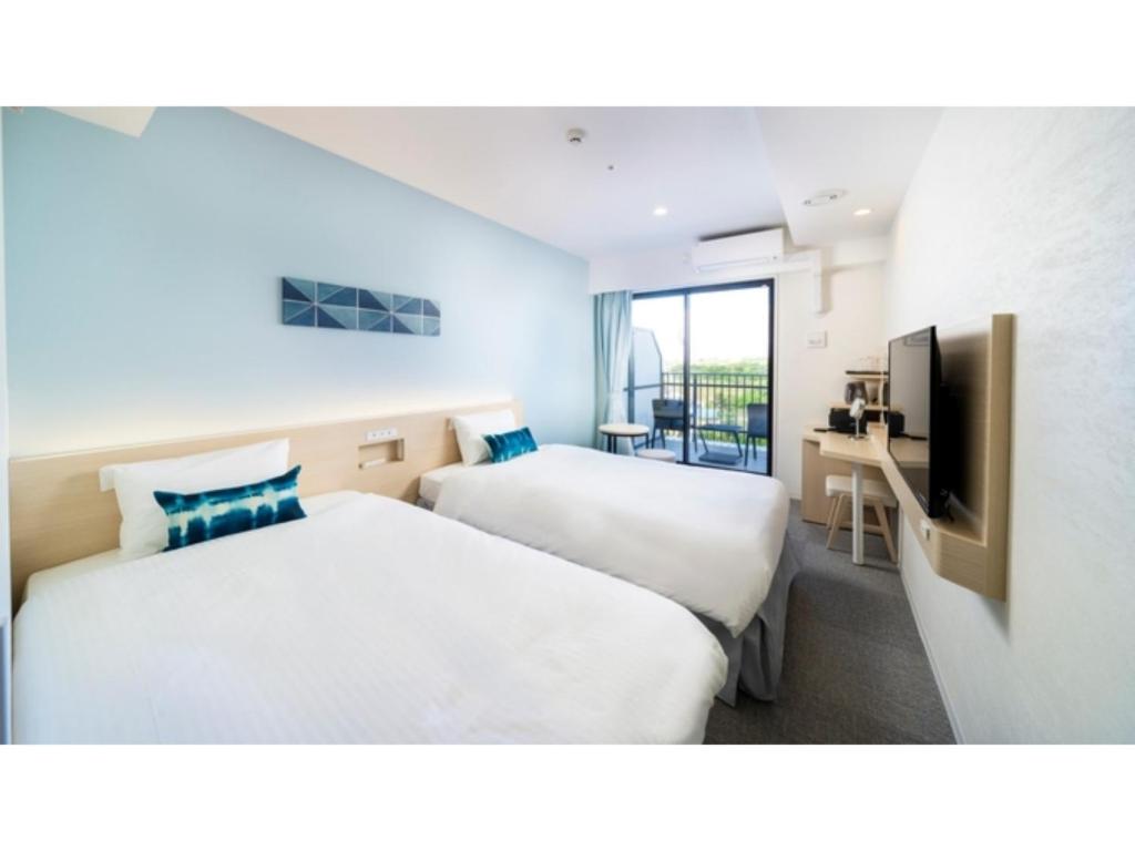 宫古岛Hotel Torifito Miyakojima Resort - Vacation STAY 79490v的酒店客房设有两张床和电视。