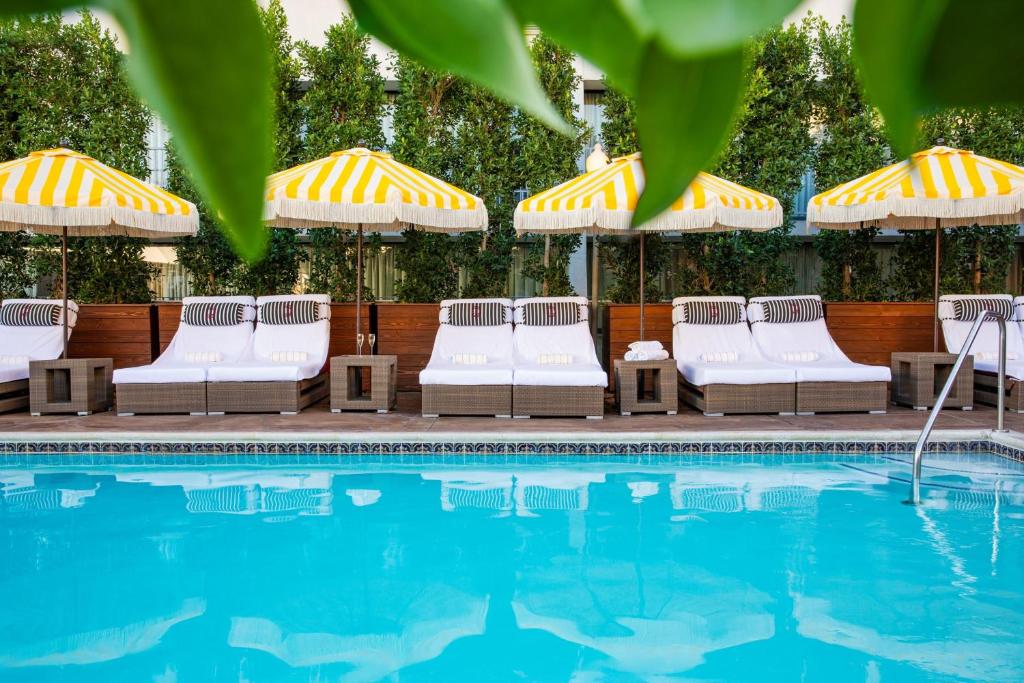 帕萨迪纳Hotel Dena, Pasadena Los Angeles, a Tribute Portfolio Hotel的游泳池旁的一排椅子和遮阳伞
