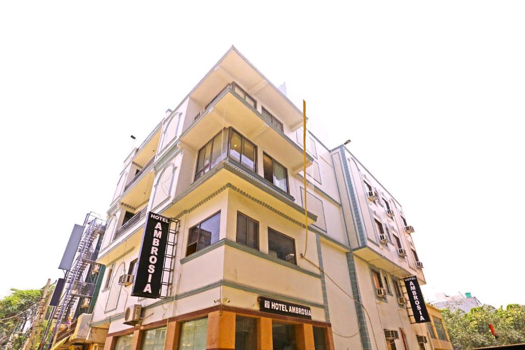 新德里Hotel Ambrosia - A Boutique Hotel的黄色和白色的建筑,上面有标志