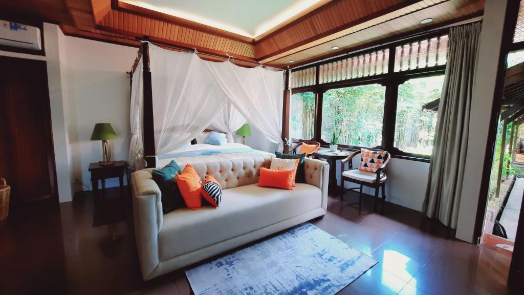 登巴萨Villia magnolia sanur bali 巴厘島玉蘭別墅的一间带白色沙发的卧室,位于带窗户的房间内