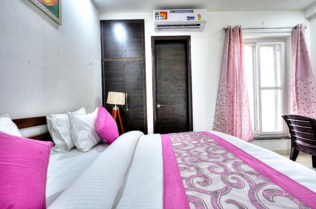 诺伊达The Noble Suites, Near Spectrum Mall的卧室配有带粉色和白色枕头的大床