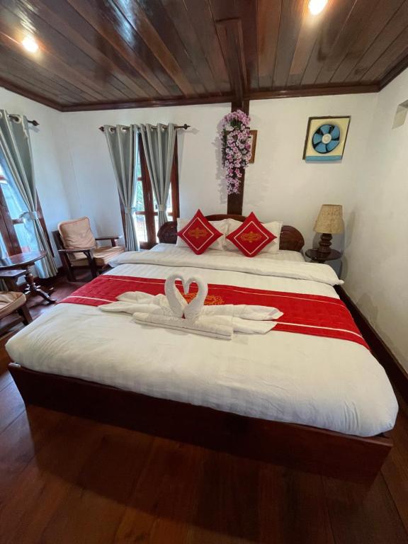 琅勃拉邦Ouis NamKhan Place House的卧室配有一张床铺,中间有2个天鹅