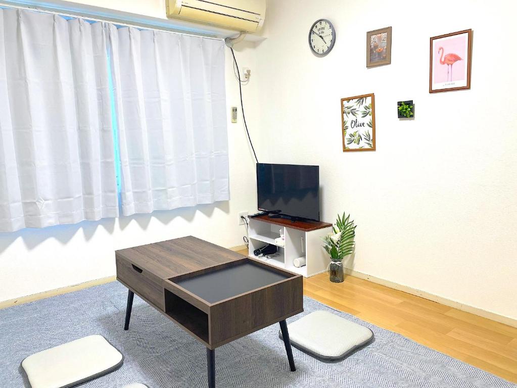 福冈FUKUOKA airport line Ijiri st self check in apartment的客厅配有咖啡桌和电视