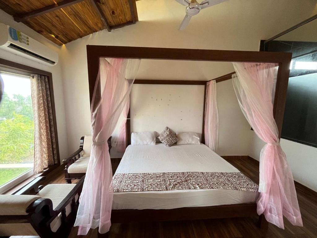 博尔本德尔Unique Resort And Restaurant的卧室配有带粉红色窗帘的天蓬床