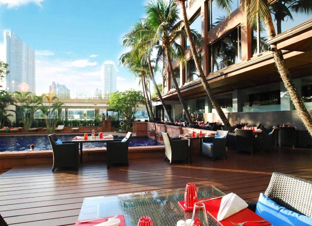 曼谷曼谷湄南河畔华美达广场酒店的大楼前设有桌椅的餐厅