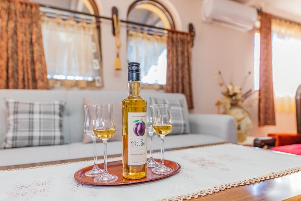 兹拉蒂博尔Vikendica Životić的桌子上放有一瓶葡萄酒和两杯酒