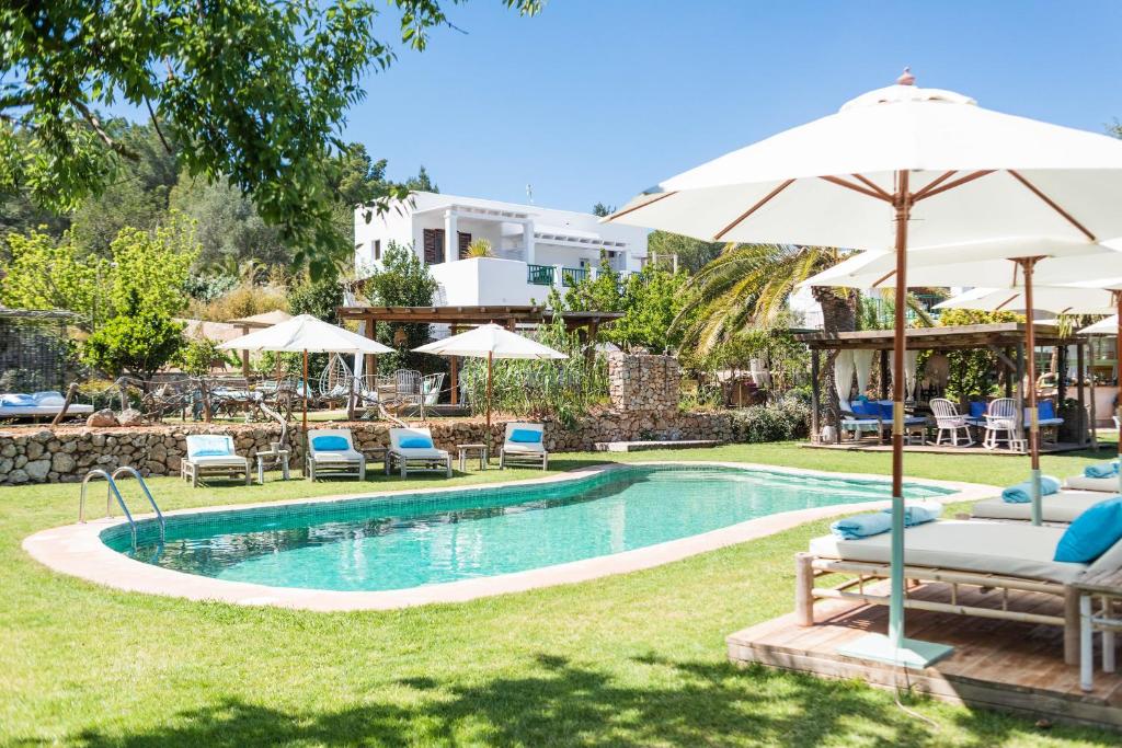 圣安东尼奥ES CUCONS RURAL HOTEL的庭院内带椅子和遮阳伞的游泳池