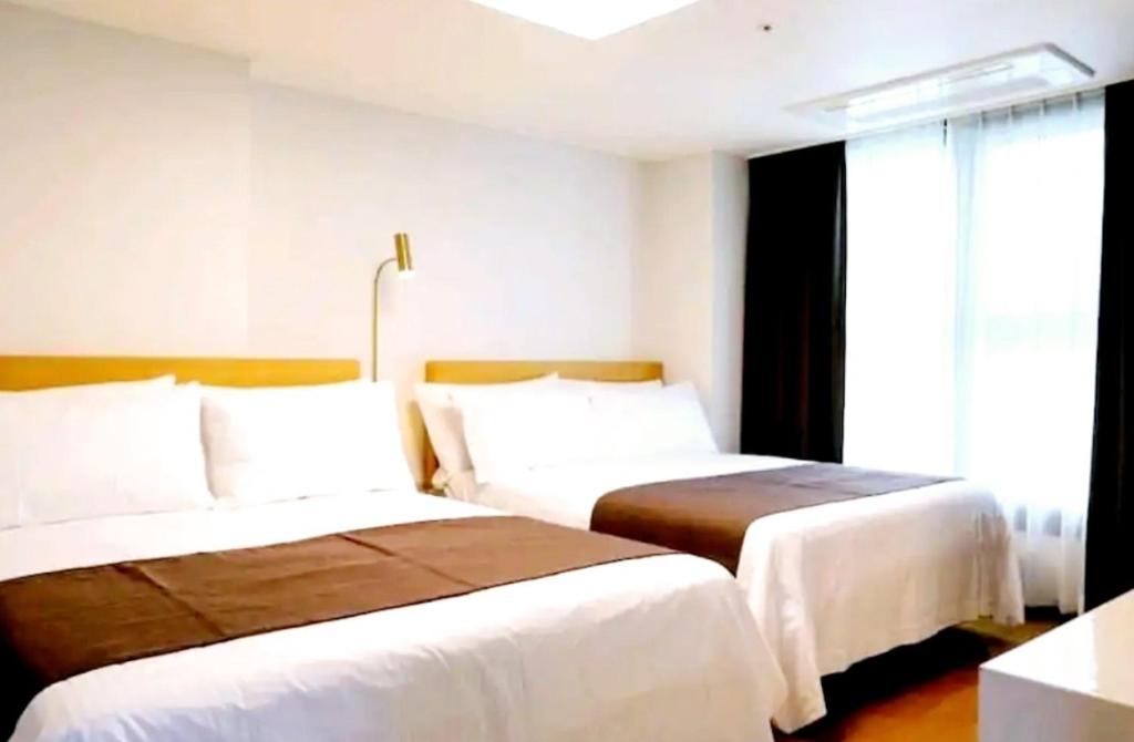 釜山Ciel de Mer的酒店客房设有两张床和窗户。