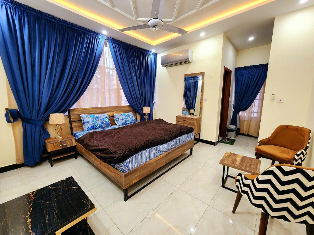 伊斯兰堡Motorway Majesty Lodges - Near Islamabad International Airport & Motorway的一间卧室配有一张床和蓝色窗帘