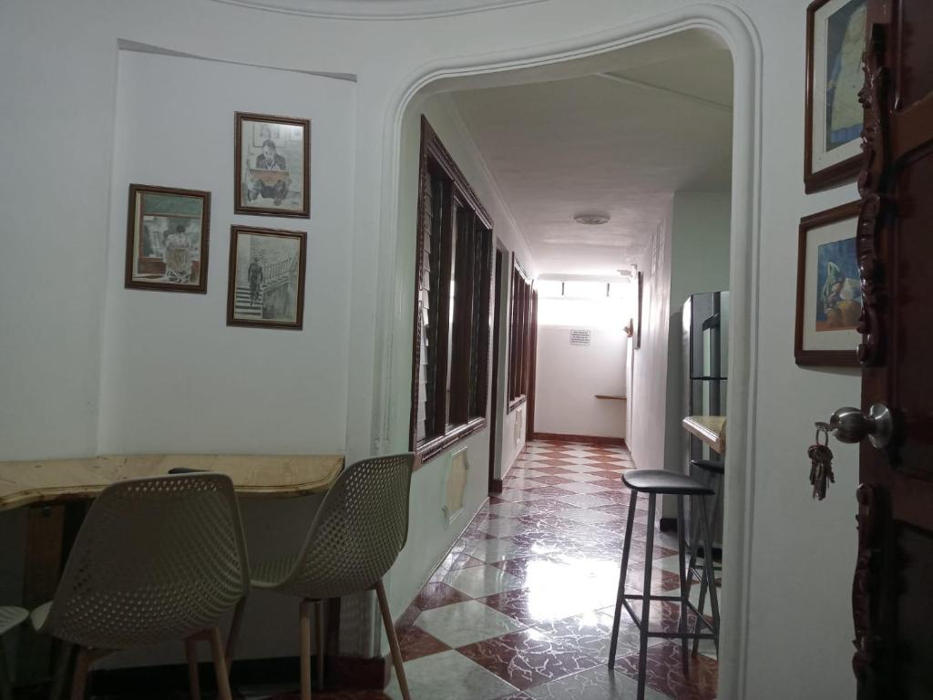 麦德林ESTADIO APARTA HOTEL 201的走廊上设有椅子和桌子,位于房子内