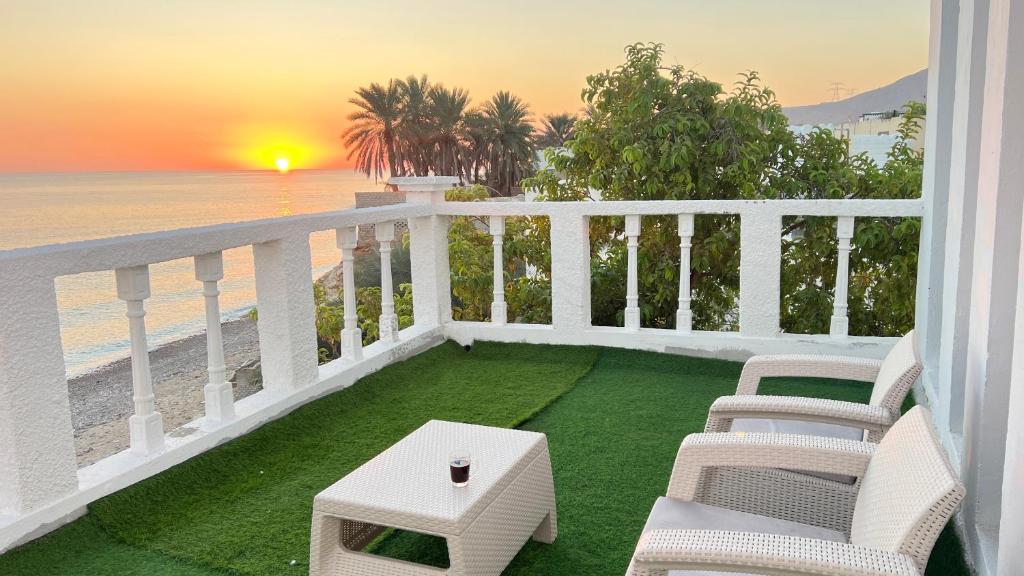 苏尔Wadi shab Rose Beach的一个带桌椅和海滩的阳台