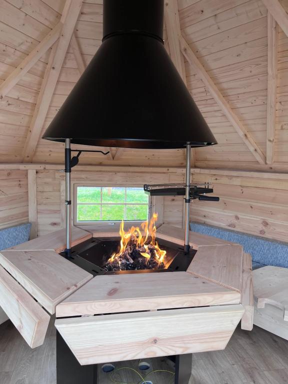 CardendenCapledrae Farmstay Shepherds Huts的小木屋内的壁炉,设有黑色天花板