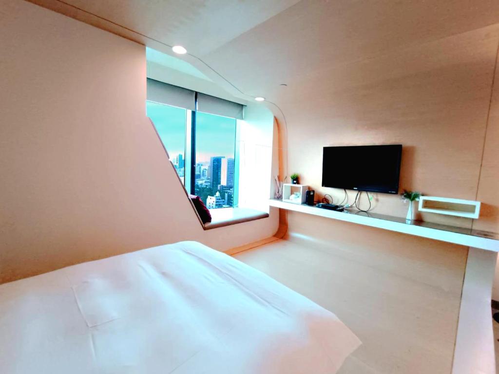 高雄三条文旅的一间卧室设有一张床和一个带电视的窗户。