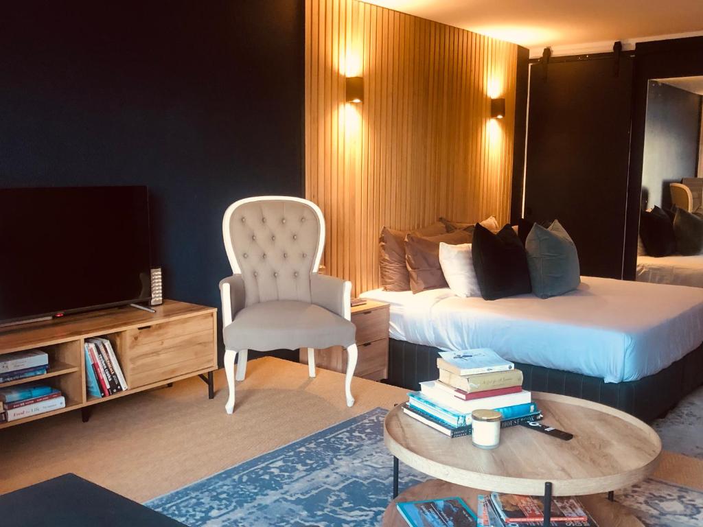 开普敦Studio Blue in Mouille Point的酒店客房带一张床、一台电视和一把椅子