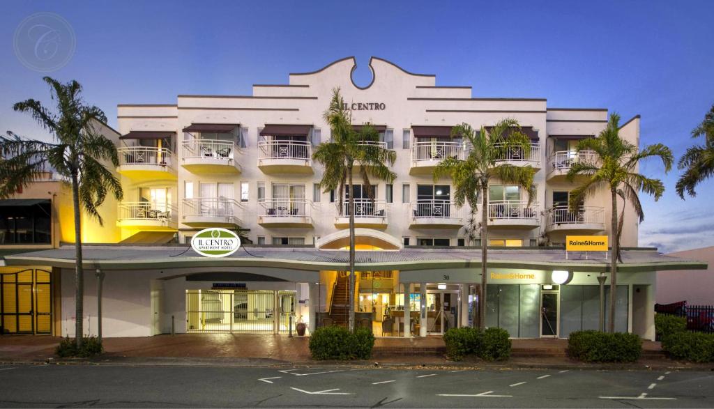 凯恩斯一号中心公寓酒店的一座白色的建筑,前面有棕榈树