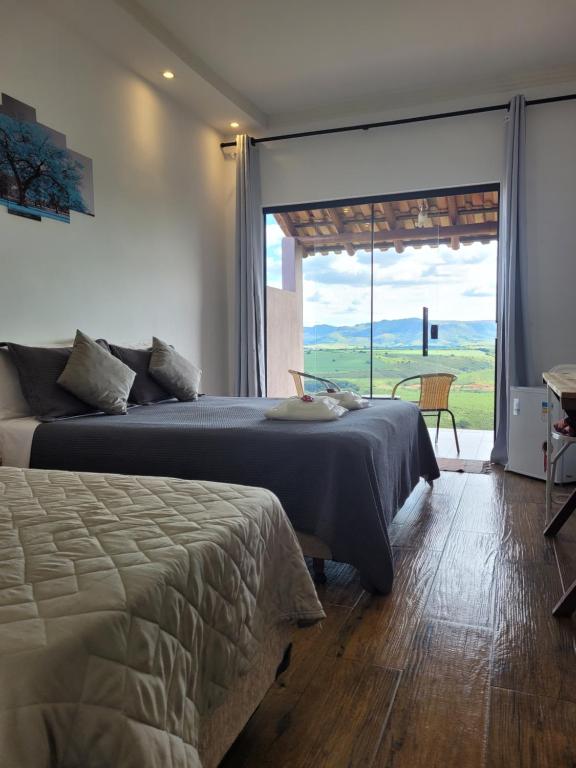 圣罗克迪米纳斯Pousada Colina da Canastra的一间卧室设有两张床和大窗户