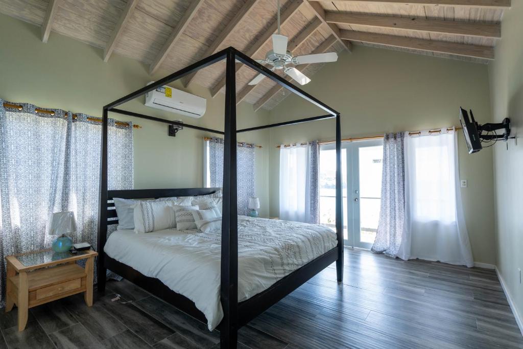 Crab HillThe Ti-Kaye Oasis的一间卧室配有一张天蓬床和吊扇