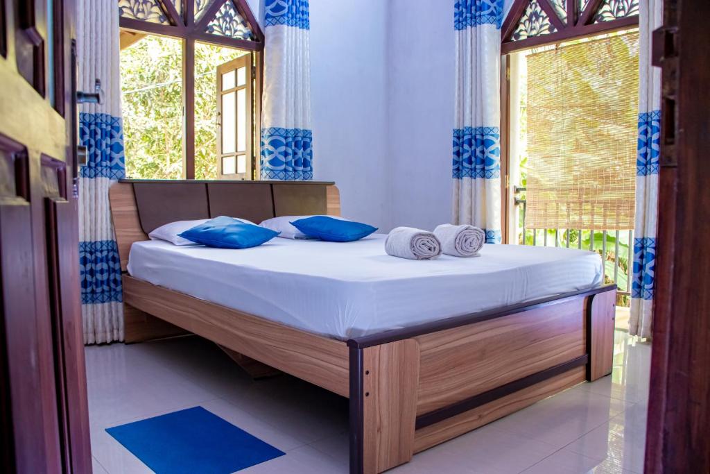 高尔DiNi Galle的一间卧室配有一张带蓝色枕头的床和一扇窗户。