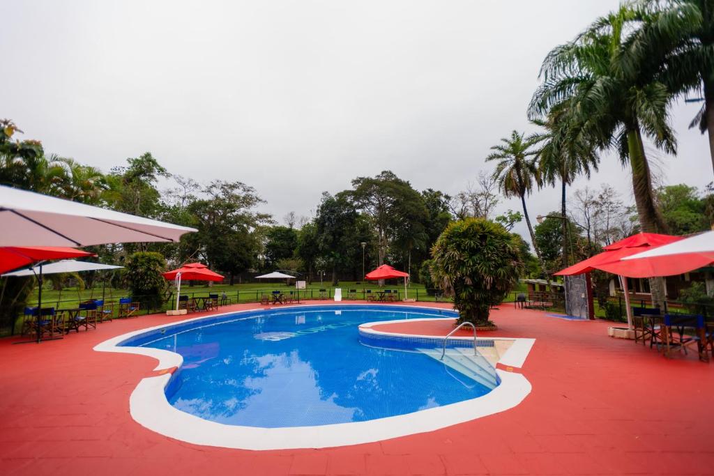 伊瓜苏港HOTEL TROPICAL IGUAZU的度假村的游泳池配有桌子和遮阳伞