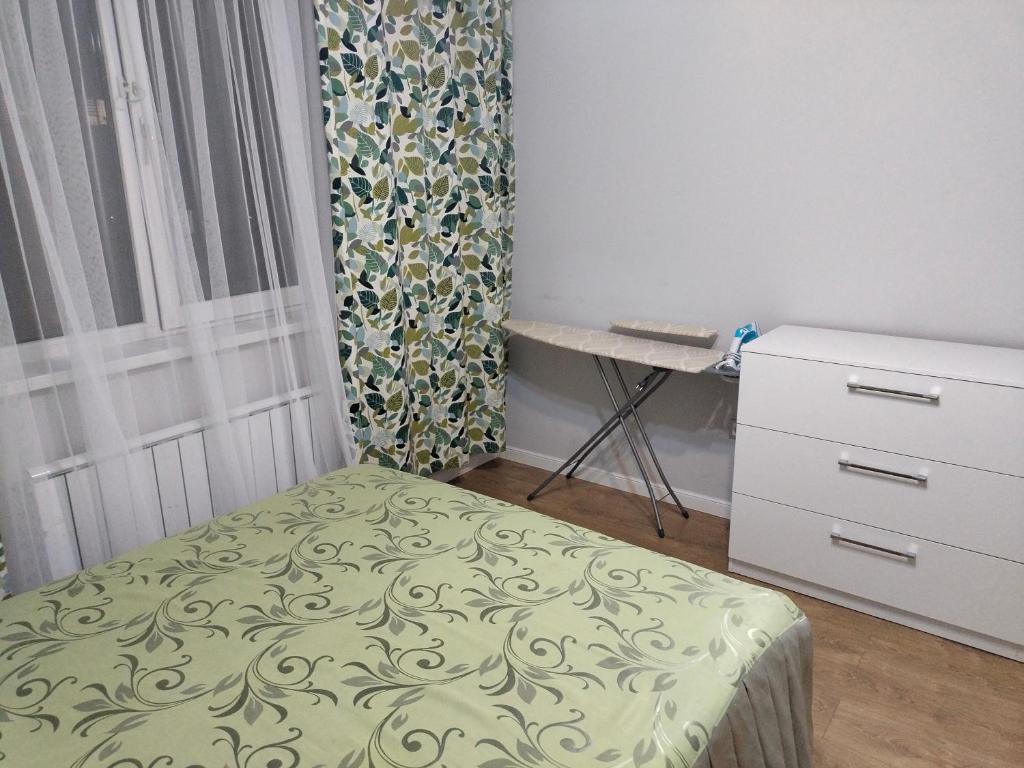 Alghabas2-я квартира Алматы Арена ЖК的一间卧室配有一张床、一个梳妆台和一扇窗户。