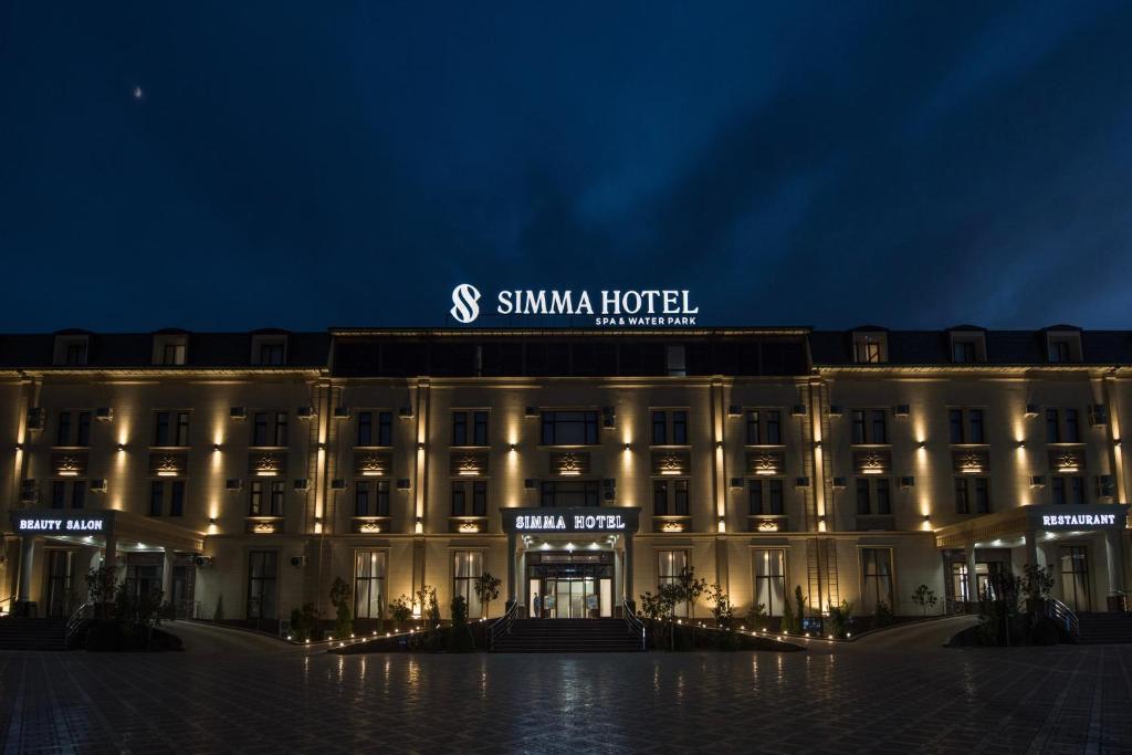 塔什干Simma Hotel Spa & Waterpark的一座建筑物,上面有夜间标志