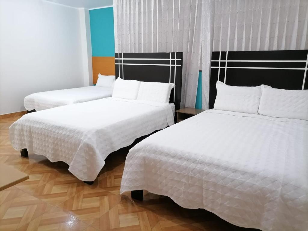 LambayequeHostal Tulipán Rojo的配有白色床单的酒店客房内的两张床