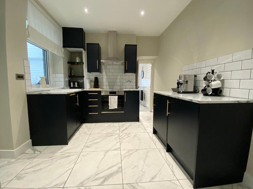 CwmcarnNewly renovated, hi-spec three bed, forest view home的大型厨房配有黑色橱柜和白色瓷砖地板。