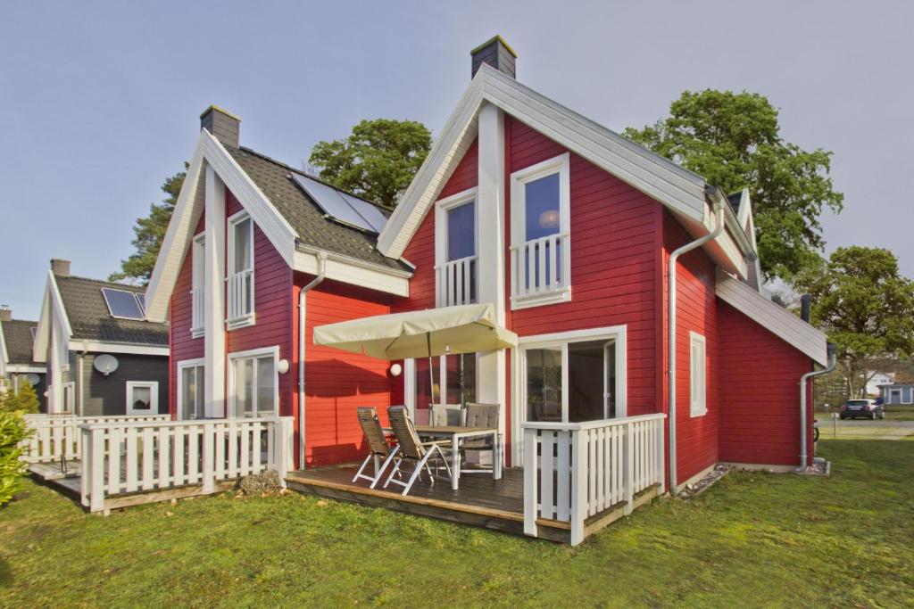 格洛韦Ferienhaus Wellenläufer Haus - Sauna, Terrasse, Garten的红色的房子,配有带桌椅的甲板