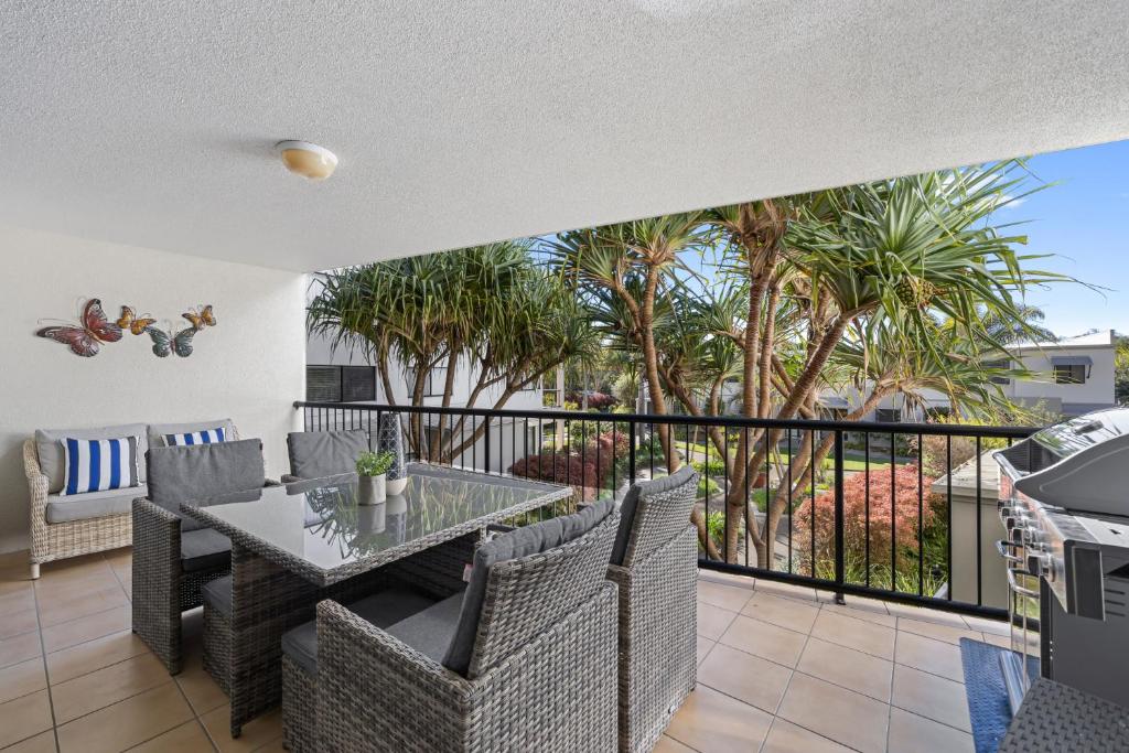 马库拉Beachside 3-Bed with Pool, BBQ, Gym & Tennis Court的阳台配有桌椅和棕榈树。